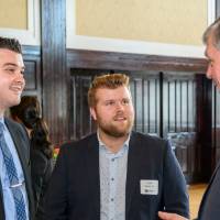 Two male alumni chat with President Haas